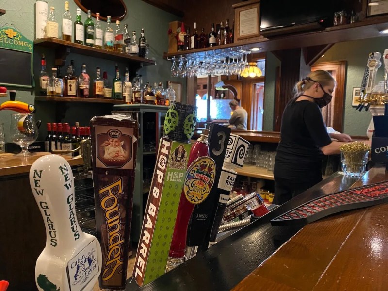 Ashley Deetz cleans the bar area at Houligans Steak & Seafood Pub in downtown Eau Claire Thursday afternoon before the restaurant opened. People working at restaurants, taverns and other service sector jobs have been among the hardest hit financially by the ongoing coronavirus pandemic. (Photo by Julian Emerson)
