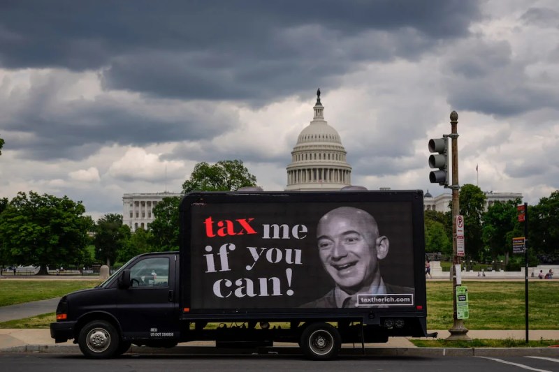 Demonstrators for tax reform frequently cite tax breaks enjoyed by pharmaceutical companies, the oil and gas industry, and individual billionaires such as businessman Jeff Bezos, whose image was depicted on a mobile billboard near the US Capitol on May 17, 2021 by the group "Patriotic Millionaires." (Photo by Drew Angerer/Getty Images)