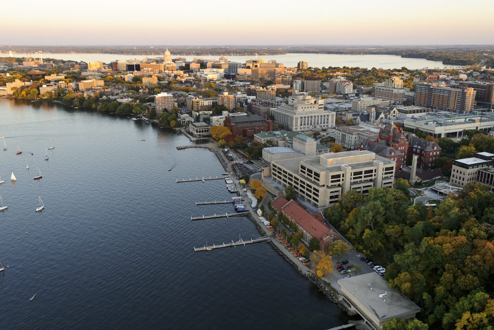 The Lake Mendota shoreline is pictured in an aerial view of the University of Wisconsin-Madison campus looking toward the downtown Madison skyline during an autumn sunset on Oct. 5, 2011. Major campus facilities pictured from center to right include Memorial Library, Armory and Gymnasium (Red Gym), the Memorial Union Terrace and Helen C. White Hall. On the horizon is the Wisconsin State Capitol and Lake Monona. The photograph was made from a helicopter looking southeast.