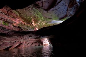 A cave formation with sunlight beaming through onto the water.