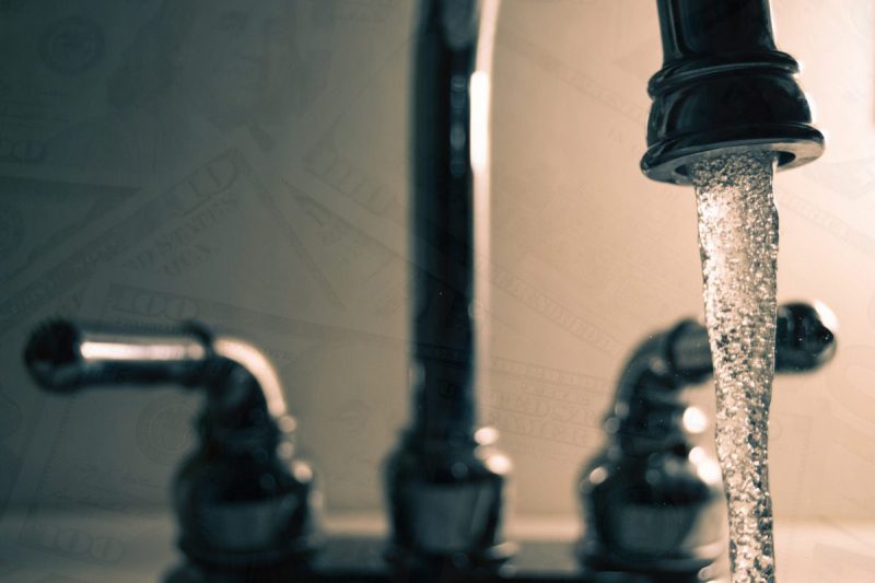Sink faucet with running water layered over image of money to represent PFAS funding