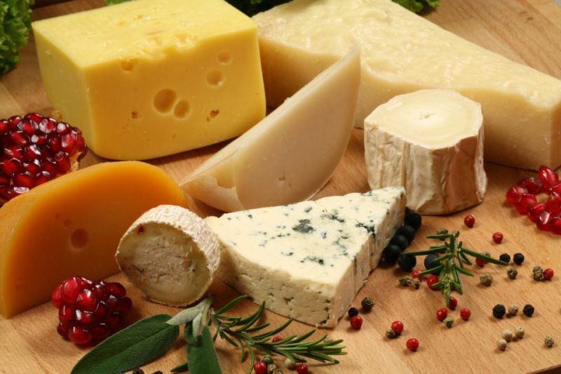 A variety of cheeses with fruit, peppercorns, and herbs.