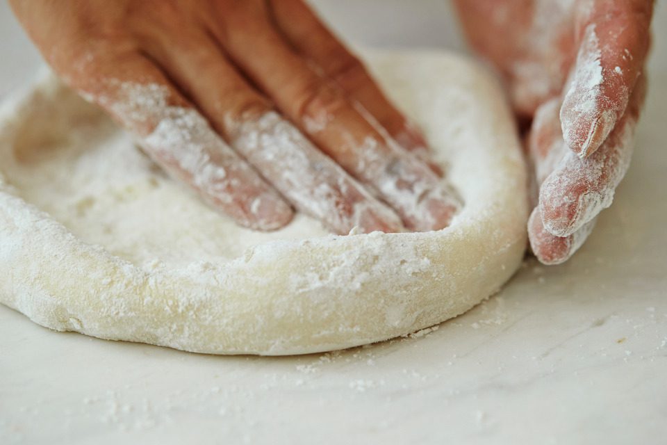 A person making pizza dough.