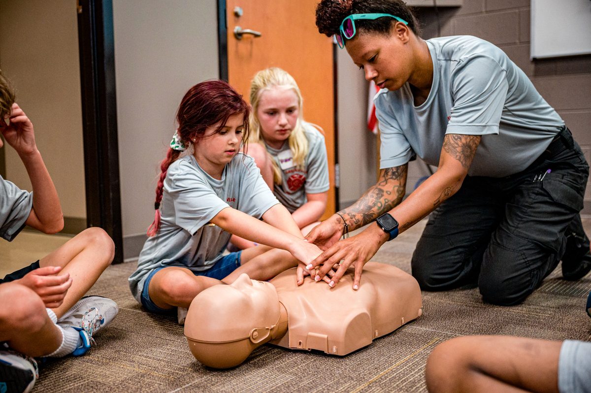 Young children being taught CPR by an instructor.