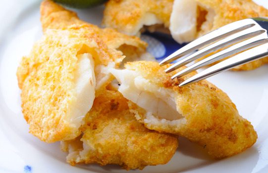 Fried fish being torn apart by a fork.