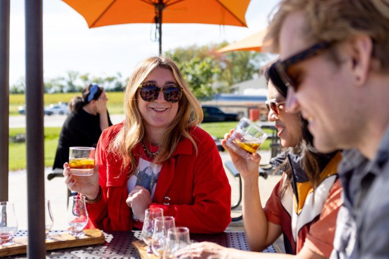 people sitting outside in the sun, talking over drinks