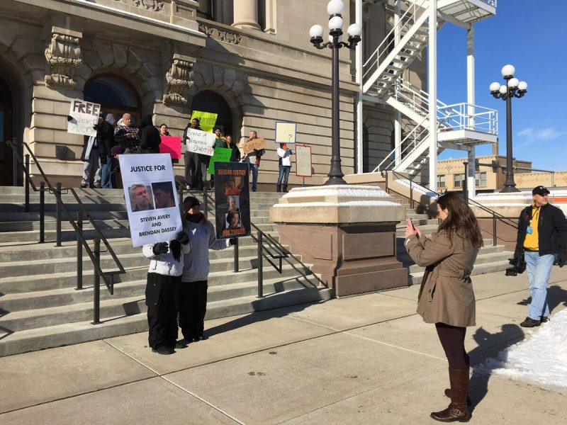 people holding signs outside of a court house