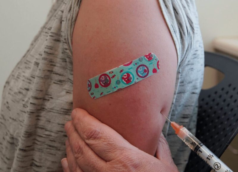 an arm with a needle injecting medication and a bandaid on it